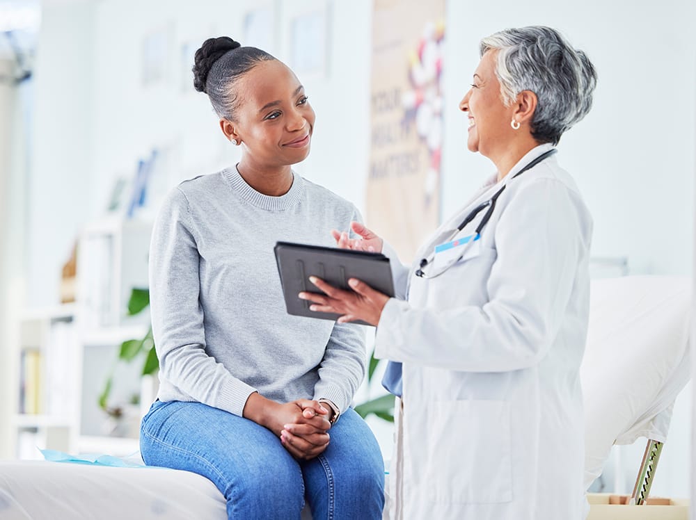 Doctor, women and tablet for happy healthcare, hospital news and support with test results or exam on bed. Senior nurse and p